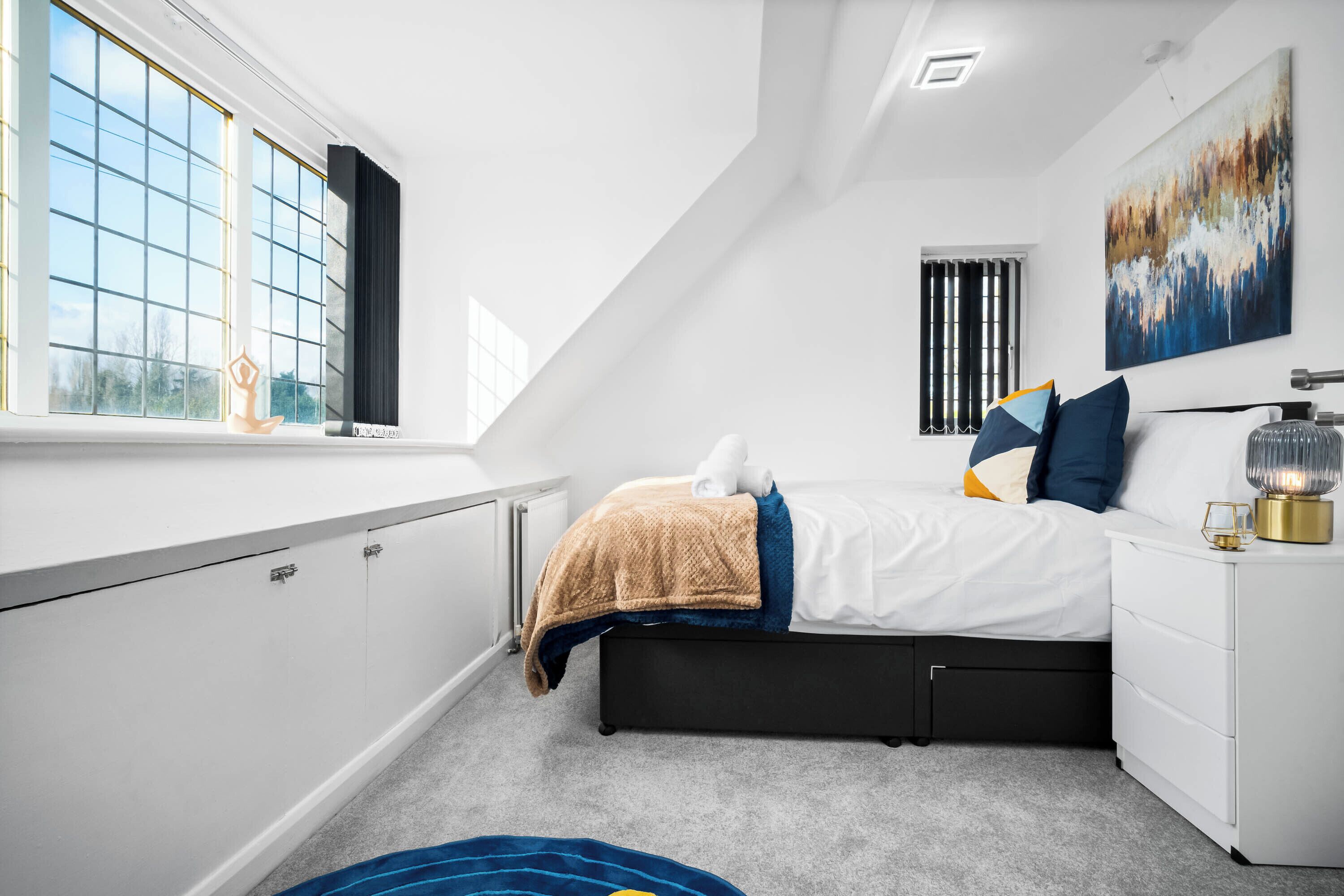 Een moderne slaapkamer met een bed, nachtkastje en raam.