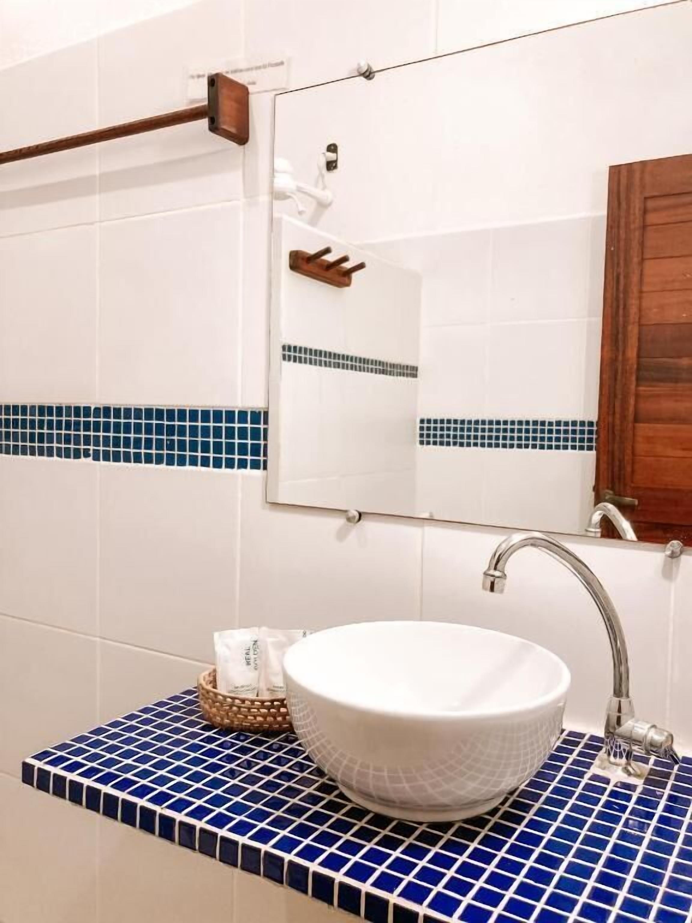 A bathroom with a white sink, blue-tiled countertop, and a wooden cabinet.