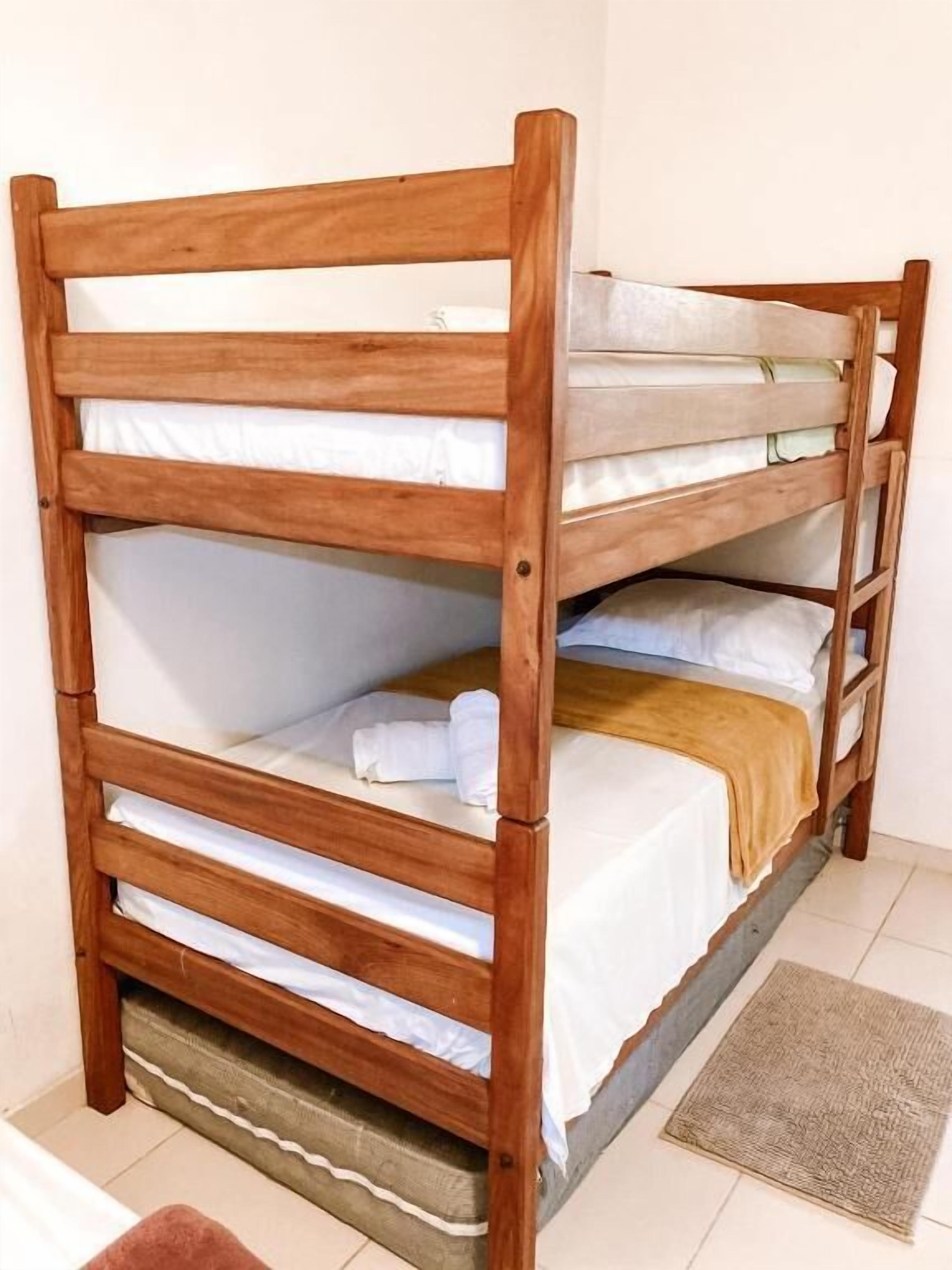 Una cama litera con estructura de madera y ropa de cama blanca.