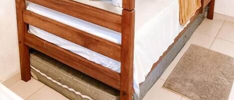 Una cama litera con estructura de madera y ropa de cama blanca.
