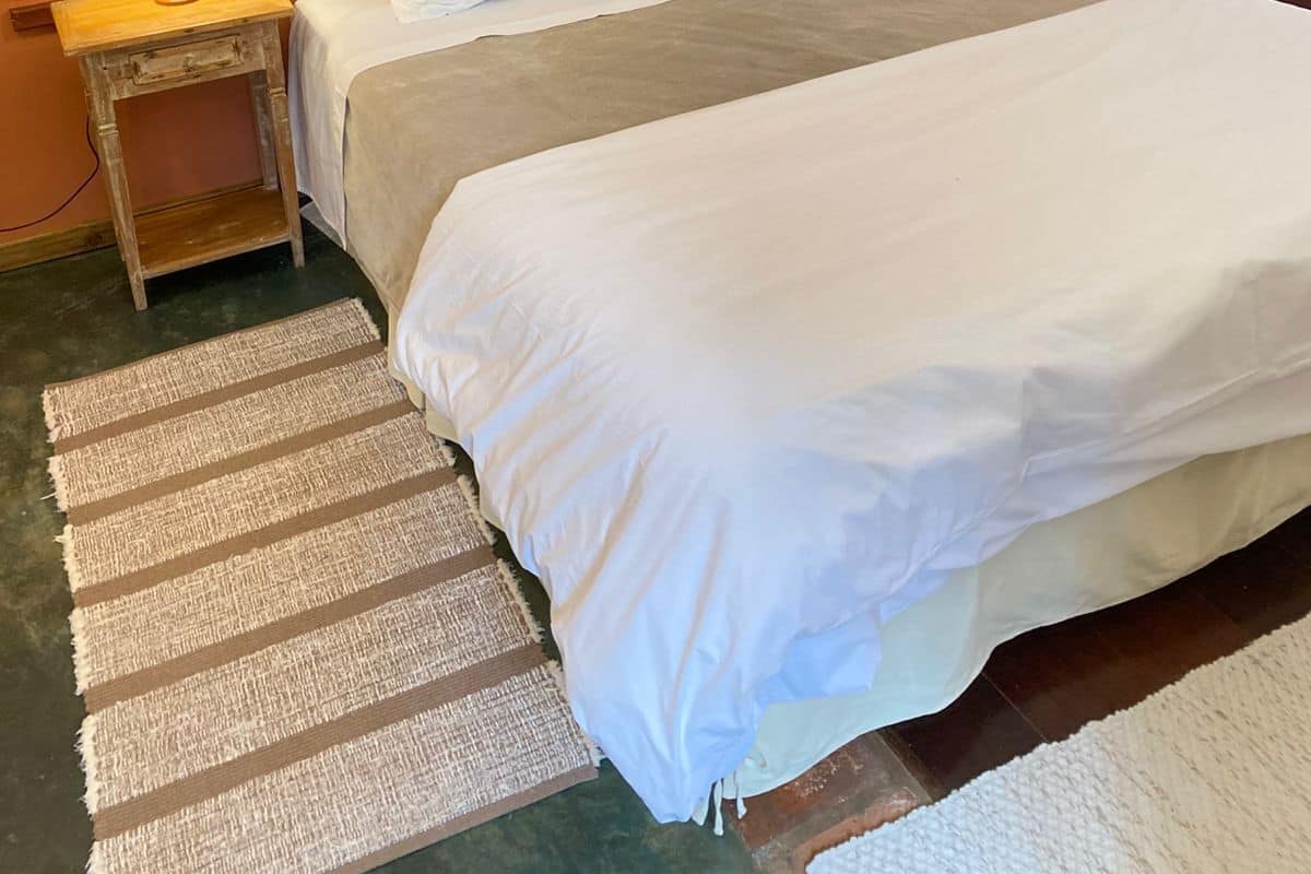 Un lit bien fait, avec du linge de lit blanc, deux tables de chevet avec des lampes, une chaise et un tableau encadré au mur.