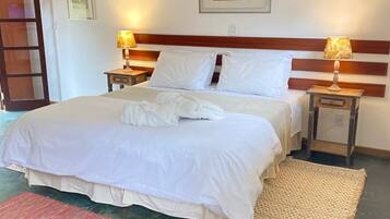 A neatly made bed with white linens and pillows, two bedside lamps, a framed picture on the wall, and a red rug on the floor.