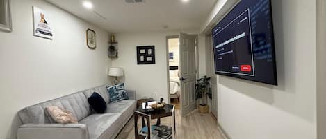 Una sala de estar moderna con un sofá gris, una mesa de centro y un televisor de pantalla plana montado en la pared.