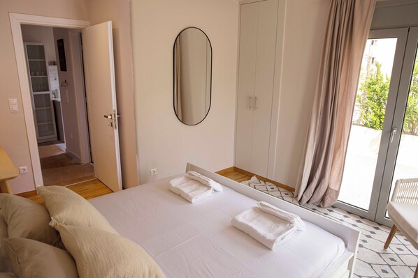 Un dormitorio con cama, espejo, armario y puerta corrediza de vidrio a un balcón.