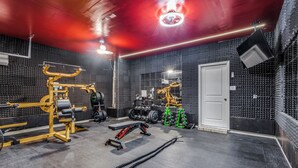Une salle de sport équipée de divers appareils d’exercice, d’un miroir et d’une porte.