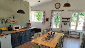 Una cucina con zona pranzo, che include un tavolo di legno, sedie, un forno a microonde e un frigorifero.