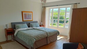 Una camera da letto con un letto grande, un comodino con una lampada, un quadro incorniciato appeso al muro e una finestra con tende.