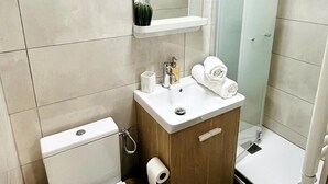 A modern bathroom with a toilet, sink, and shower. - L'écrin Bleu - Studio Cosy Intra-Muros (Lunel)