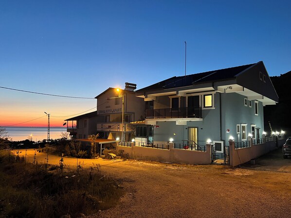 A two-story building with a balcony, a sign reading "CINAR KOYU APART," and a view of the sea at dusk. - Beşer Turizm - Avşa Adası Çınar Koyu (Marmara)