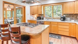 Eine moderne Küche mit Holzschränken, Granit Arbeitsplatten, einer zentralen Kochinsel und einem Essbereich mit Stühlen.