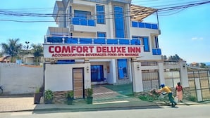 Ein zweistöckiges Gebäude mit einem Schild für 'COMFORT DELUXE INN', das Unterkunft, Getränke, Speisen und Spa-Massagen anbietet.