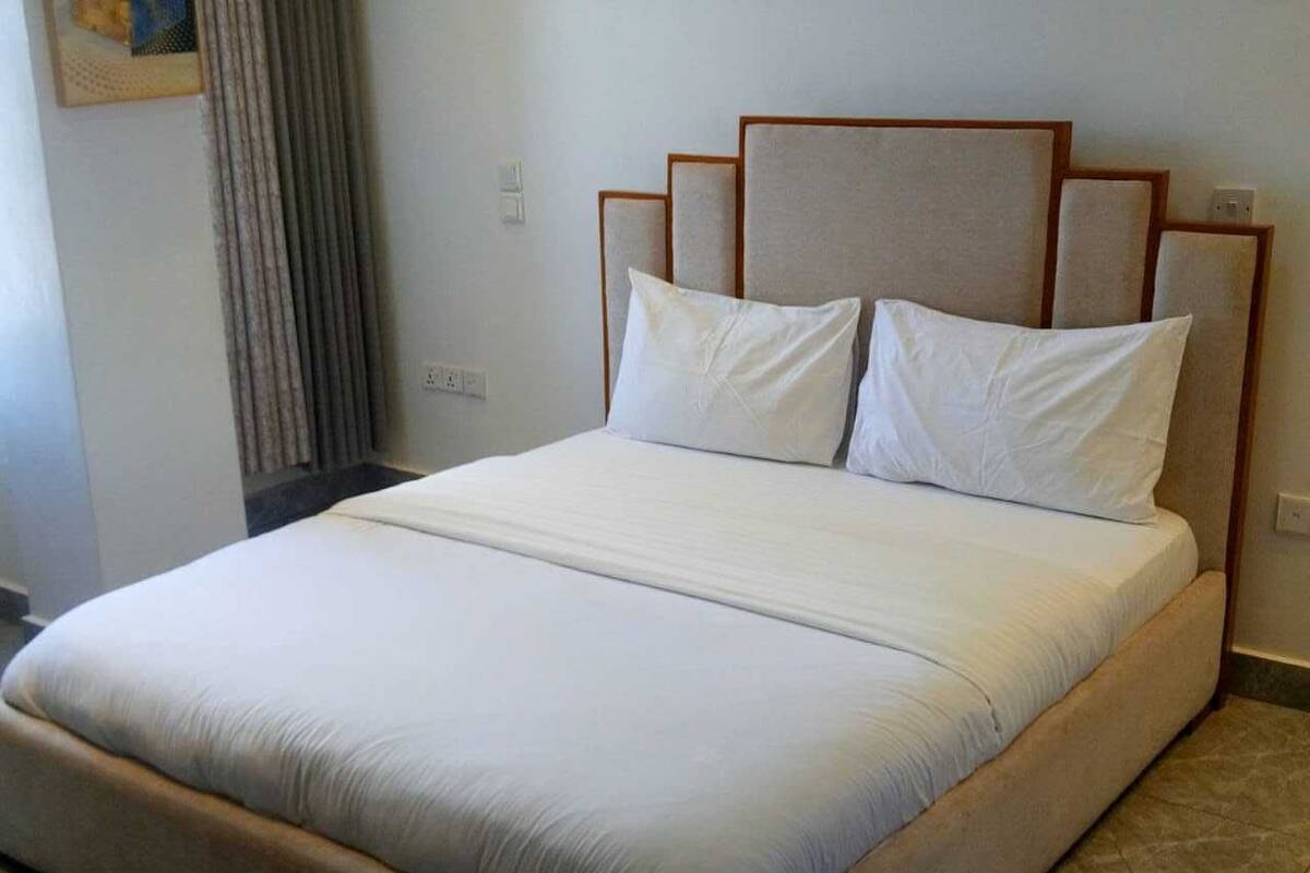 A neatly made bed with a wooden headboard and white bedding in a hotel room.