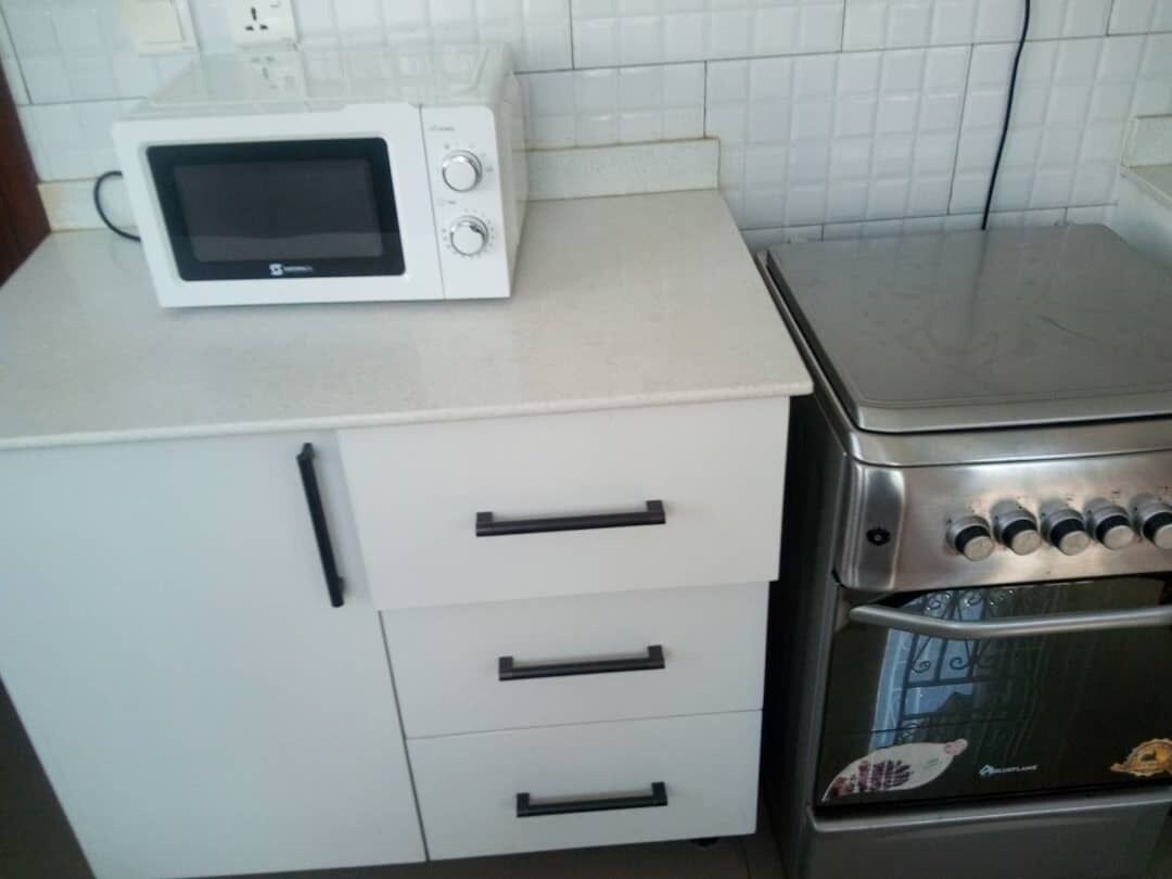 A kitchenette with a microwave, a stove, and a refrigerator.