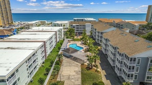 A resort with multiple buildings, a swimming pool, and a view of the ocean.