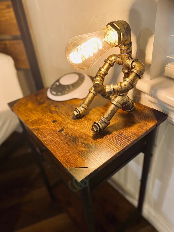 A rustic table with a vintage-style lamp featuring a light bulb and a brass base.