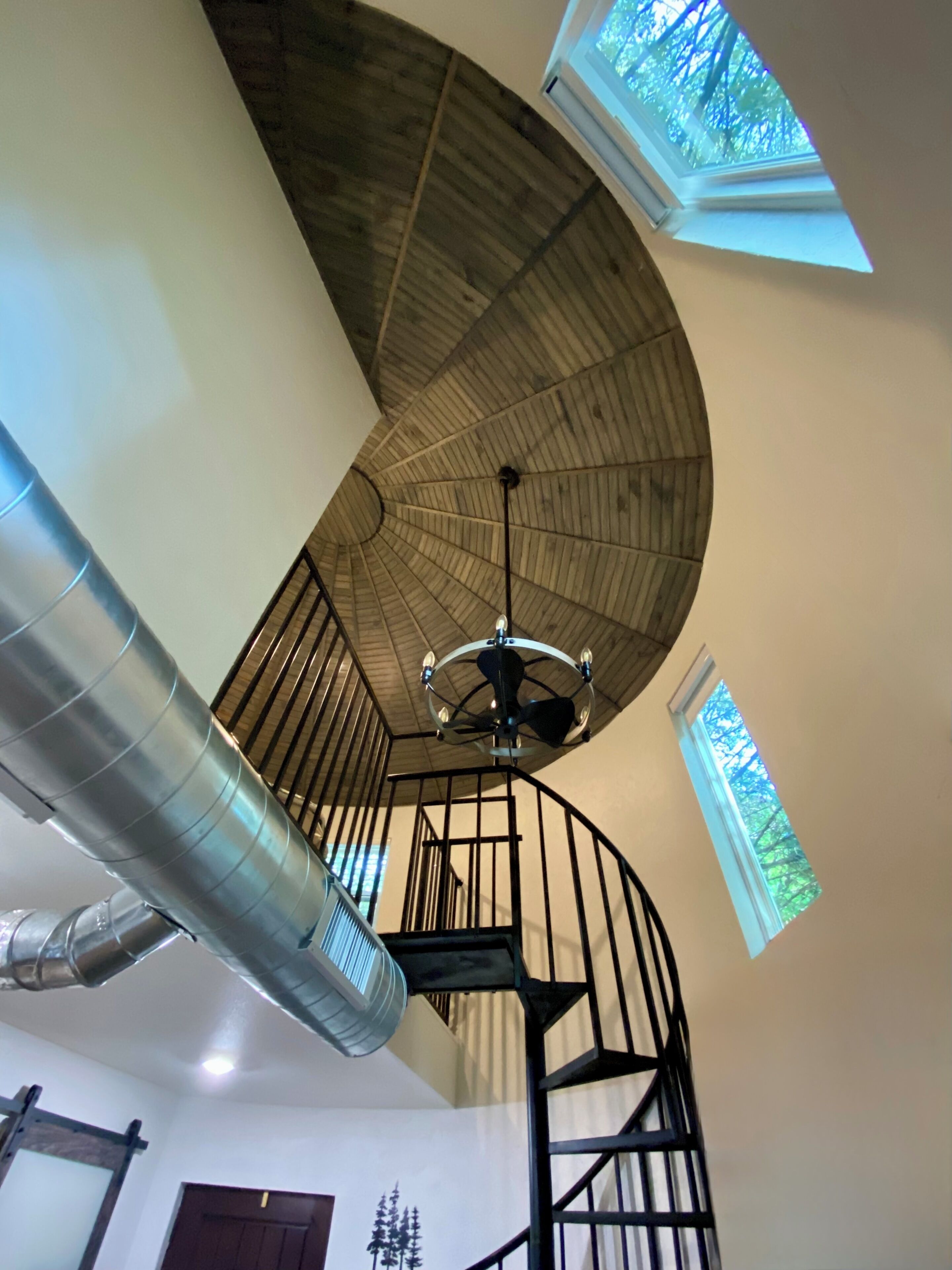 A spiral staircase with a wooden ceiling and skylights.