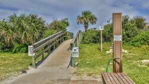 A wooden boardwalk leading to a beach area with signs indicating no animals allowed and a warning about water being off.