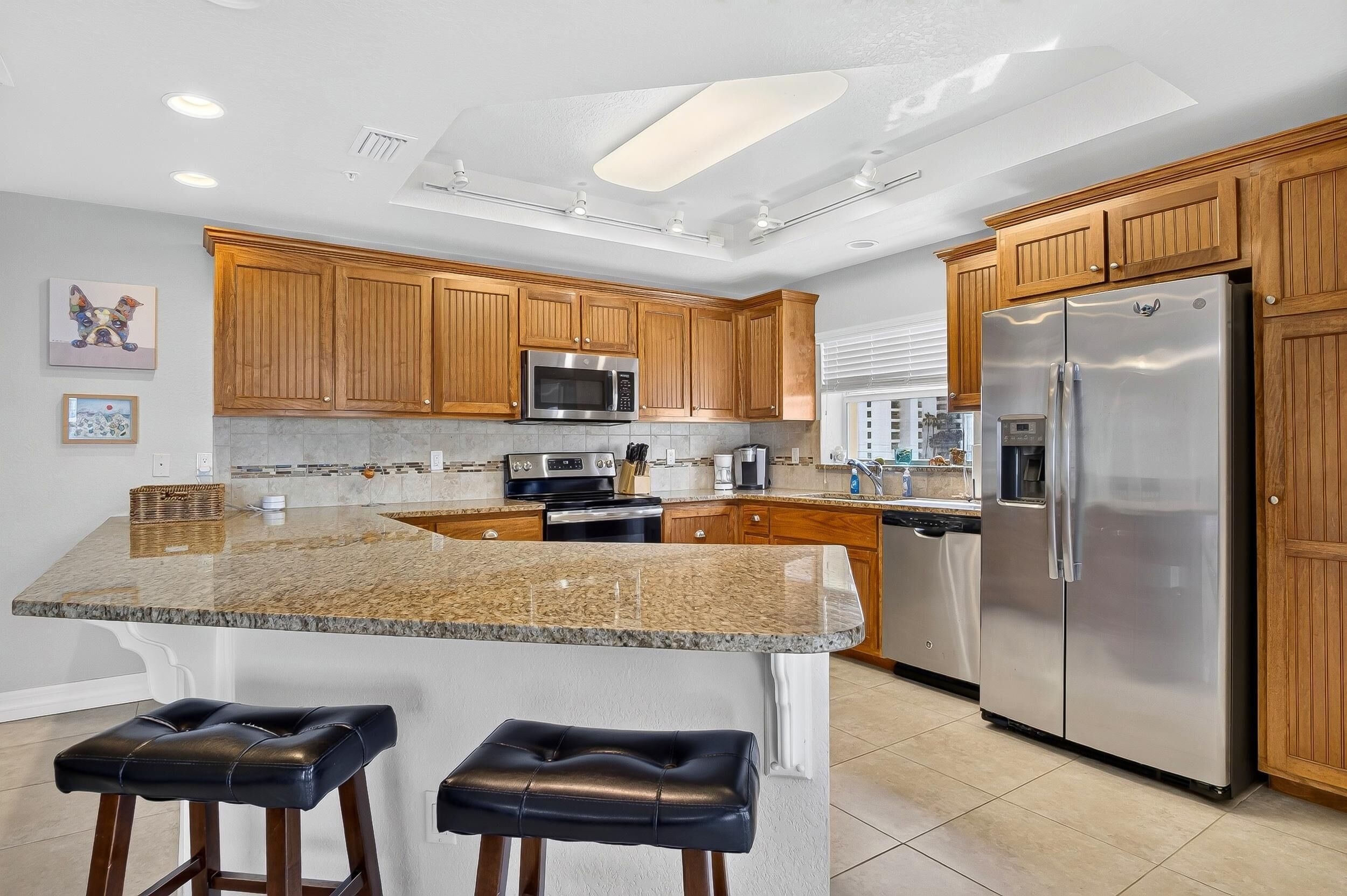 A modern kitchen with wooden cabinets, stainless steel appliances, and a granite countertop.