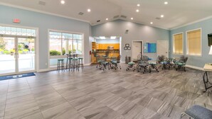 A spacious room with a kitchen area, dining tables, and chairs.