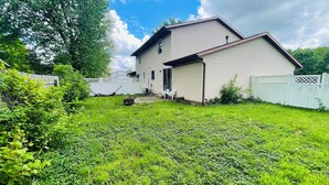 A house with a front yard, a white fence, and a clear sky. - Spacious 3BR Home w/ 8 Beds, Big Yard & Parking – Near Canton & Hall of Fame (Massillon)