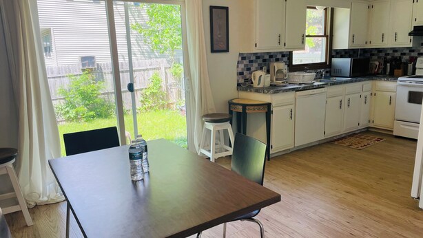 A kitchen with white cabinets, a dining table with chairs, a refrigerator, and a microwave. - Spacious 3BR Home w/ 8 Beds, Big Yard & Parking – Near Canton & Hall of Fame (Massillon)