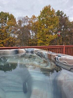 A hot tub with a marble-like texture, surrounded by a red railing, with trees in the background.