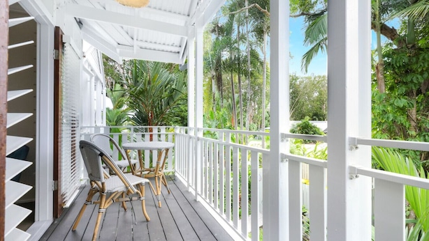 A covered porch with white railings, two wicker chairs, and a table.