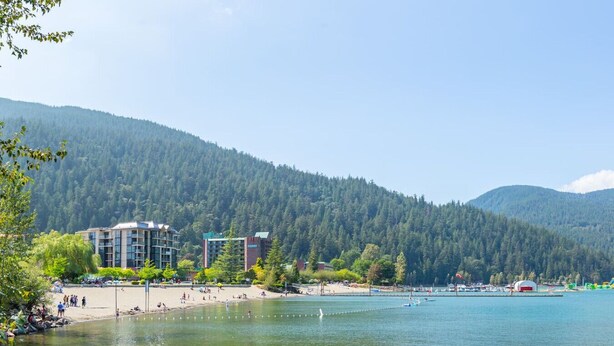 A lakeside hotel with a beach, surrounded by forested hills. - The Driftwalk | Walkable to Beach (Harrison Hot Springs)