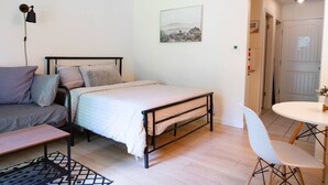 Une chambre à coucher comprenant un lit, une table de chevet, une chaise et un bureau avec une autre chaise.