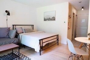 Um quarto com cama, mesa de cabeceira, cadeira e escrivaninha com cadeira.