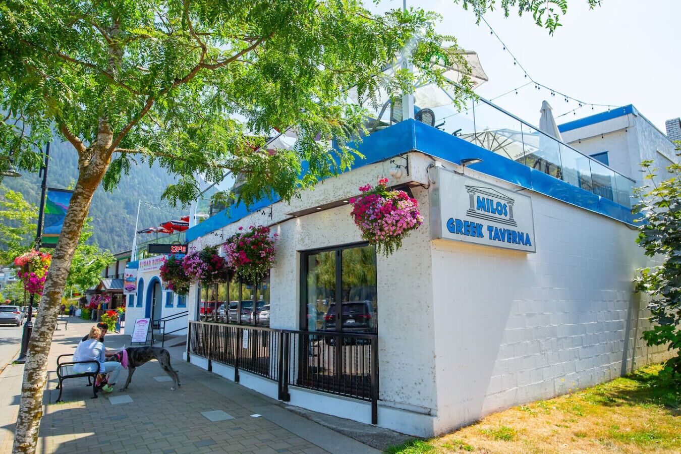 Un bâtiment blanc avec un toit bleu et une enseigne indiquant « Milos, taverne grecque ».