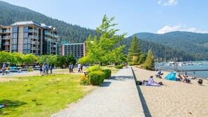 Un hôtel à étages, une allée pavée et une zone de plage où se trouvent des personnes et des tentes.