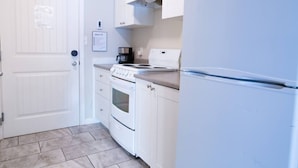 Une cuisine avec des armoires blanches, une cuisinière, une machine à café et un réfrigérateur.