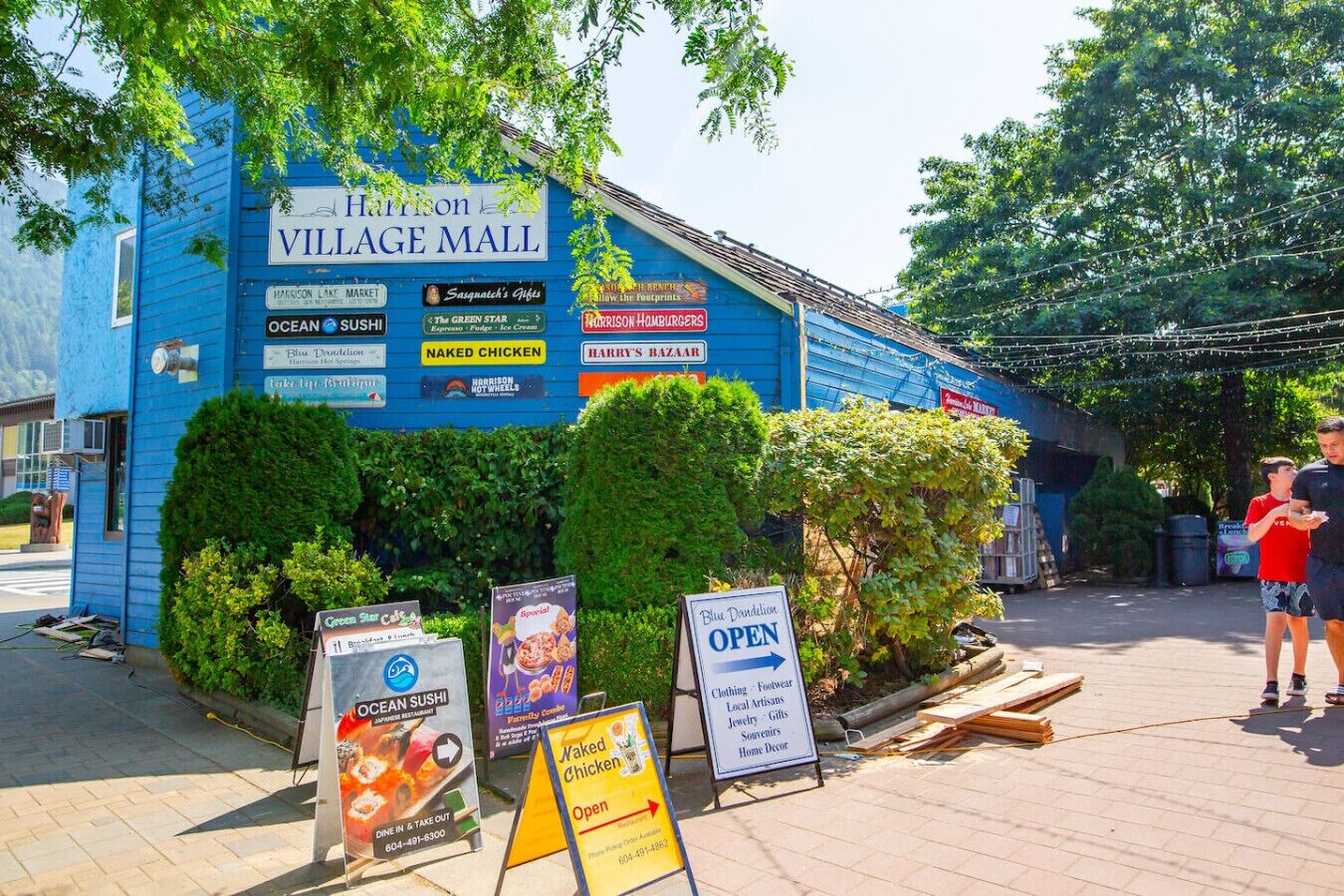 A blue building with multiple signs advertising various businesses, including a sushi restaurant and a clothing store.
