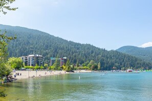 Un hôtel situé au bord d’un lac, avec une plage, et entouré de collines boisées.