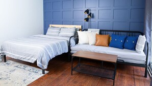 A bedroom with two beds, a bench, and a wall-mounted light fixture. - The Backyard @ Cedar Springs | Walk to Lake & Hot Springs (Harrison Hot Springs)