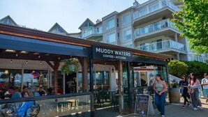 Un café llamado 'Muddy Waters' con terraza y un letrero que anuncia servicio de café y cocina.