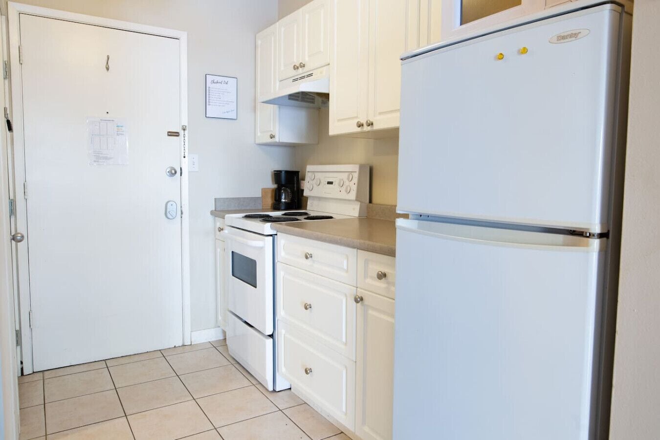 A compact kitchen with white cabinetry, a stove, an oven, and a refrigerator.