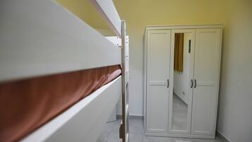 A bunk bed with a brown mattress, a white wardrobe with two doors, and a yellow wall.