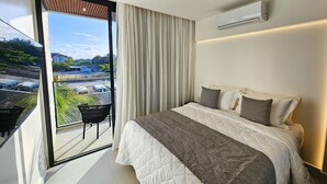 Une chambre moderne avec un grand lit, une vue sur la côte et un climatiseur fixé au mur.
