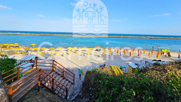 Une plage avec des parasols, un escalier et une vue sur la mer.