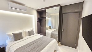 Une chambre d’hôtel moderne dotée d’un grand lit, d’un dressing et d’un miroir qui reflète la pièce.