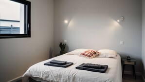 A bedroom with a large bed, two bedside tables, a window, and a view of the outside. - Modern villa with Spa 10 pers (santec)