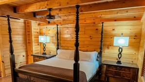 A four-poster bed with a wooden headboard, two bedside tables with lamps, and a ceiling fan. - Luxury cabin getaway on a 40 acre retreat (Bismarck)