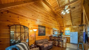 A cozy cabin interior with a wooden interior, a sofa, a dining area, and a kitchen. - Luxury cabin getaway on a 40 acre retreat (Bismarck)