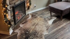 Un salon chaleureux avec une cheminée, un téléviseur et un coin salon confortable.
