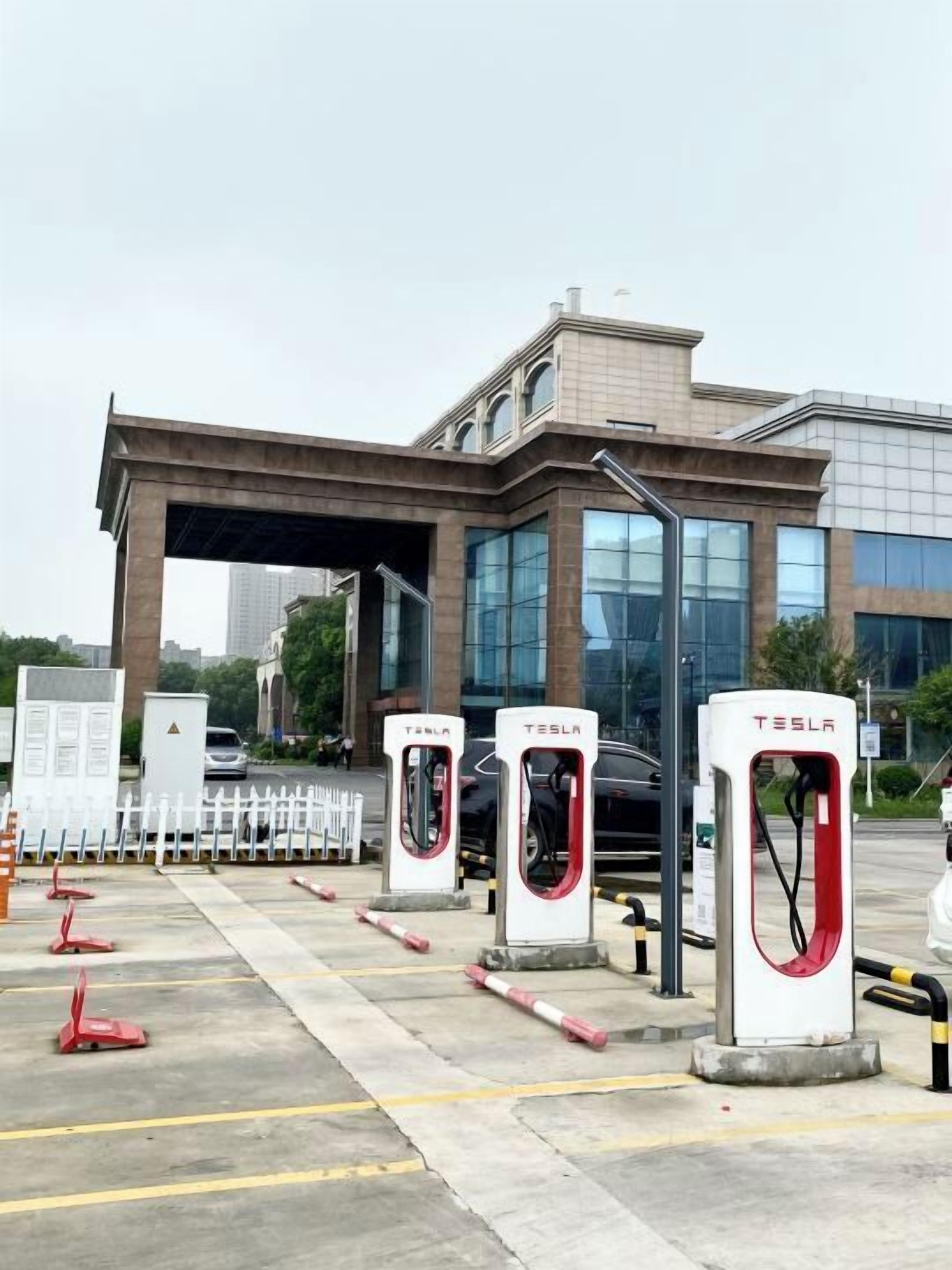 Un área de estacionamiento con tres estaciones de carga para vehículos eléctricos Tesla.