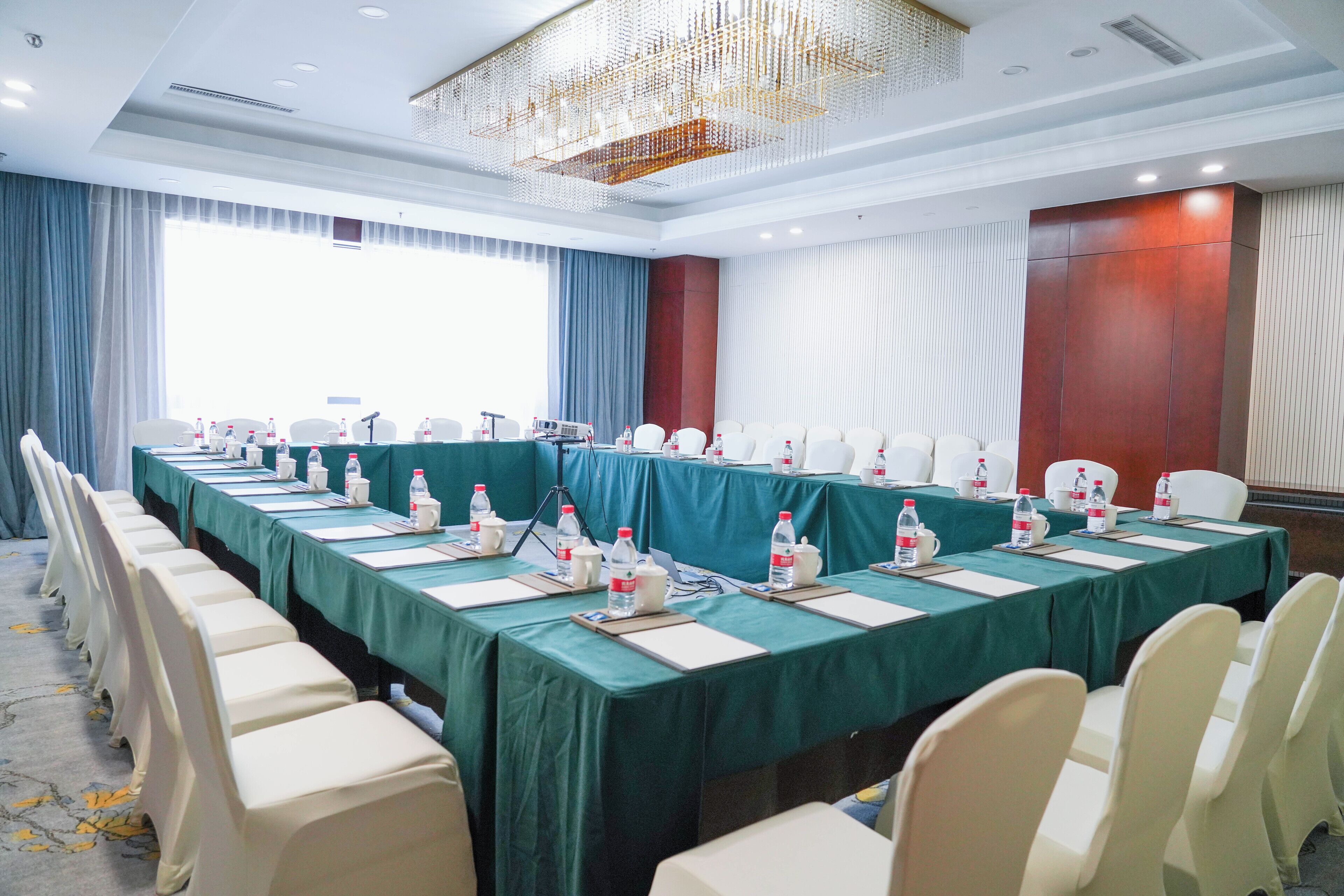 Un salón de conferencias con una mesa larga, sillas y botellas de agua.