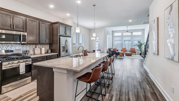 A modern kitchen with dark wood cabinets, stainless steel appliances, and a central island with bar stools.