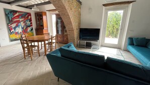 Una sala de estar con televisión, sofá y comedor.